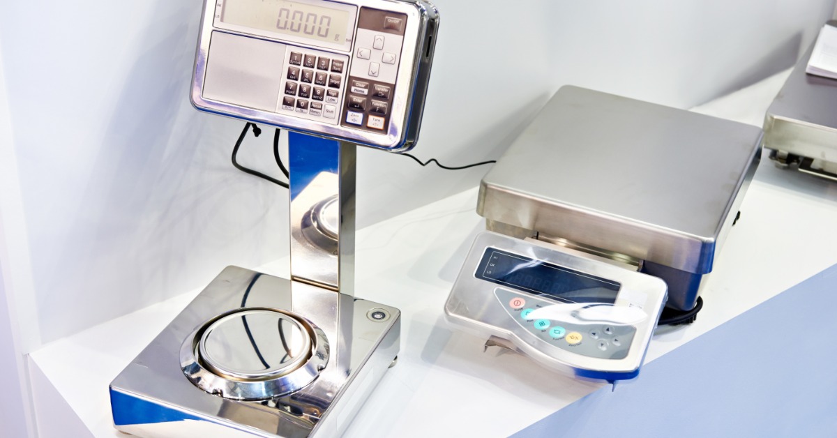 Several digital laboratory scales sit on a counter, including a larger platform scale and smaller precision devices.